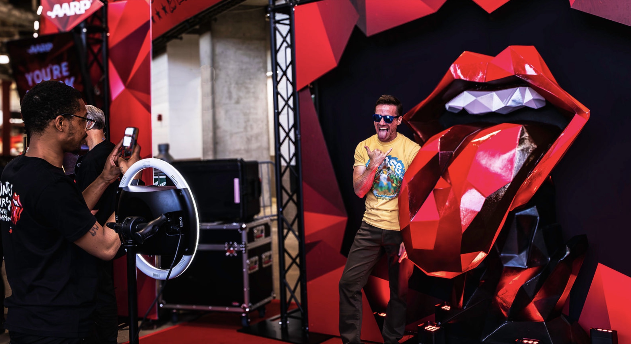AARP branded Rolling Stones fan activation with a guest posing by the red lips installation